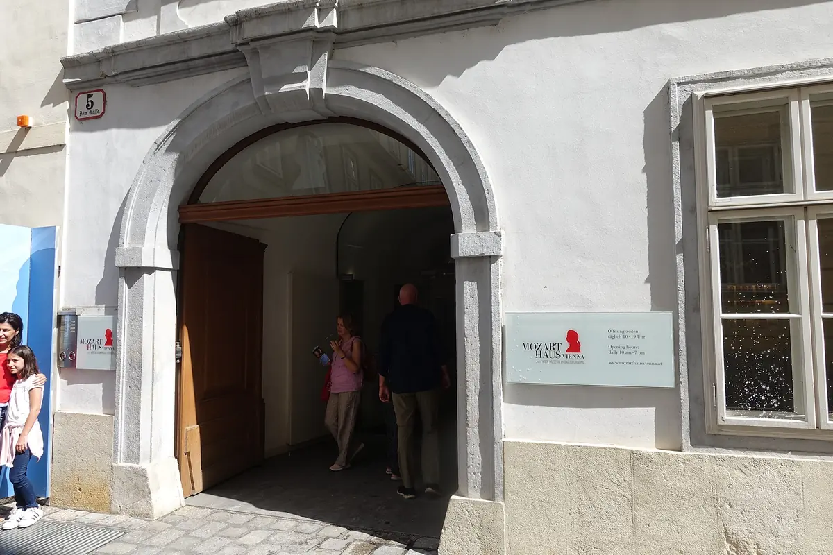 Łukowe wejście do muzeum Mozarthaus Vienna przy Domgasse 5, z numerem domu na ścianie i wchodzącymi zwiedzającymi.